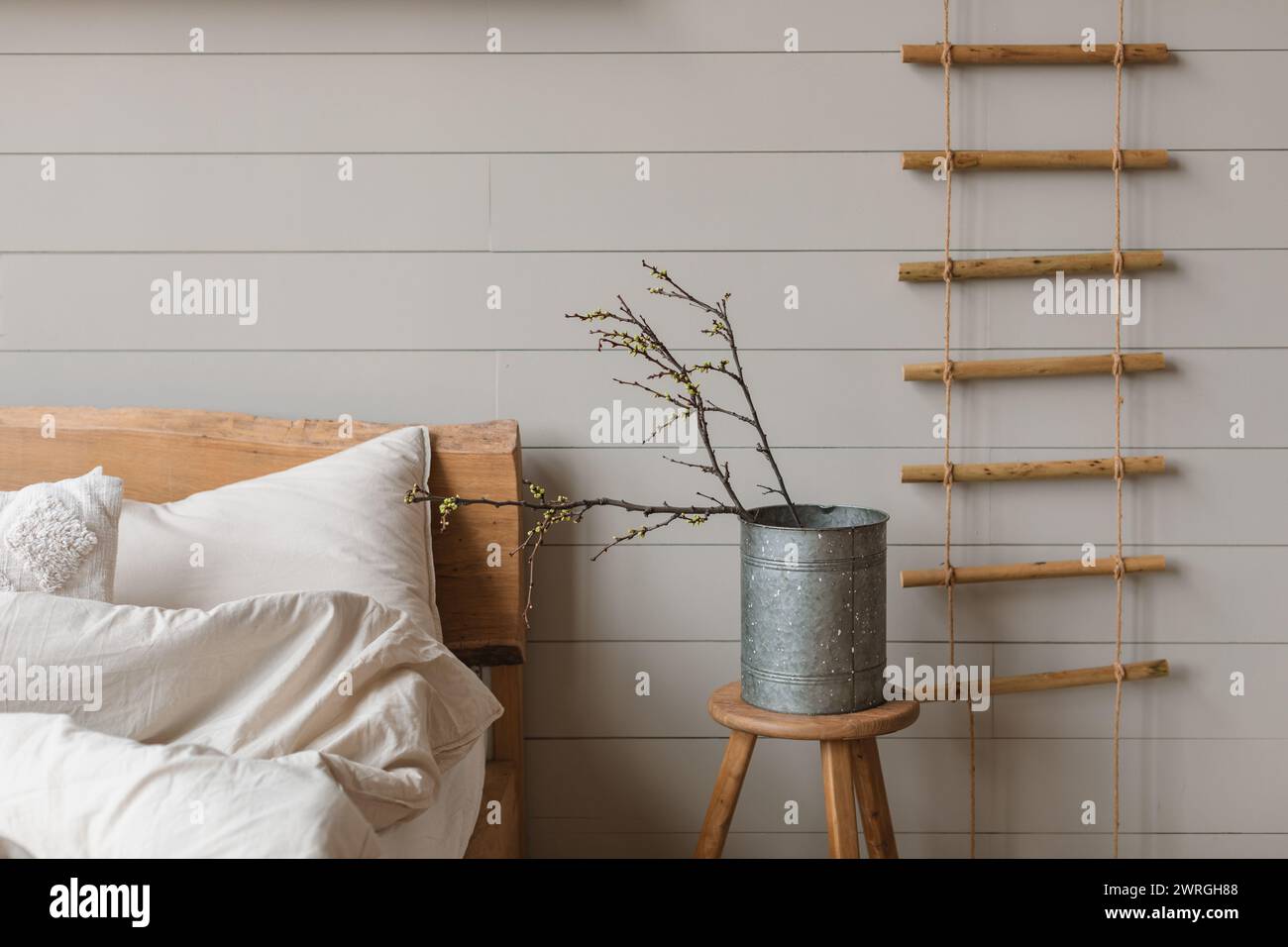 Vaso con rametti di prugna ciliegia su un comodino accanto a un letto non fatto in una camera da letto Foto Stock