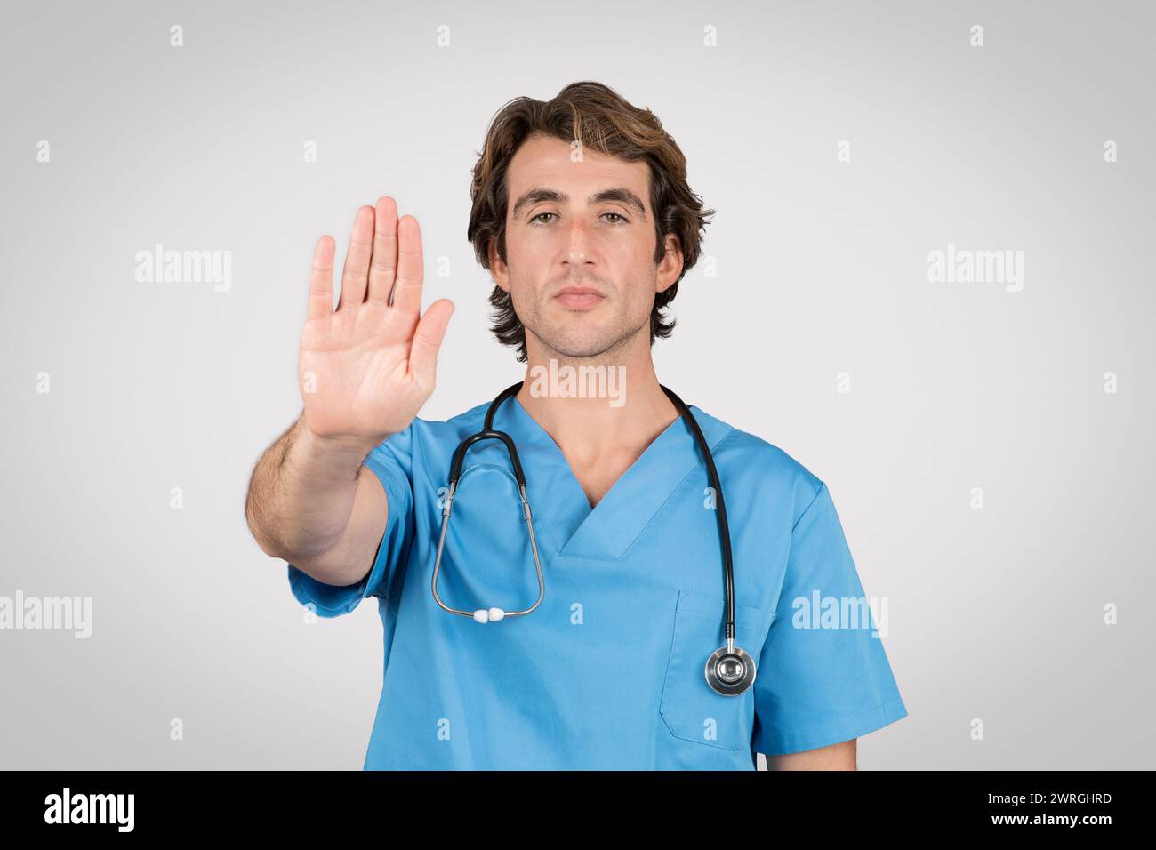 Maschio medico professionista in scrub blu gesturing stop Foto Stock