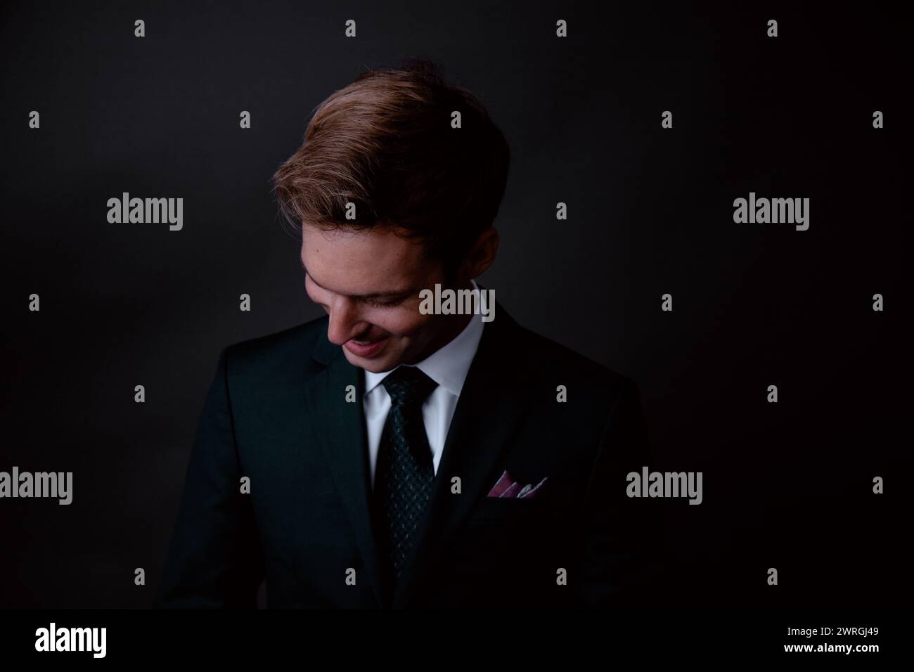 Primo piano ritratto di un uomo d'affari sorridente con un abito che guarda in basso Foto Stock