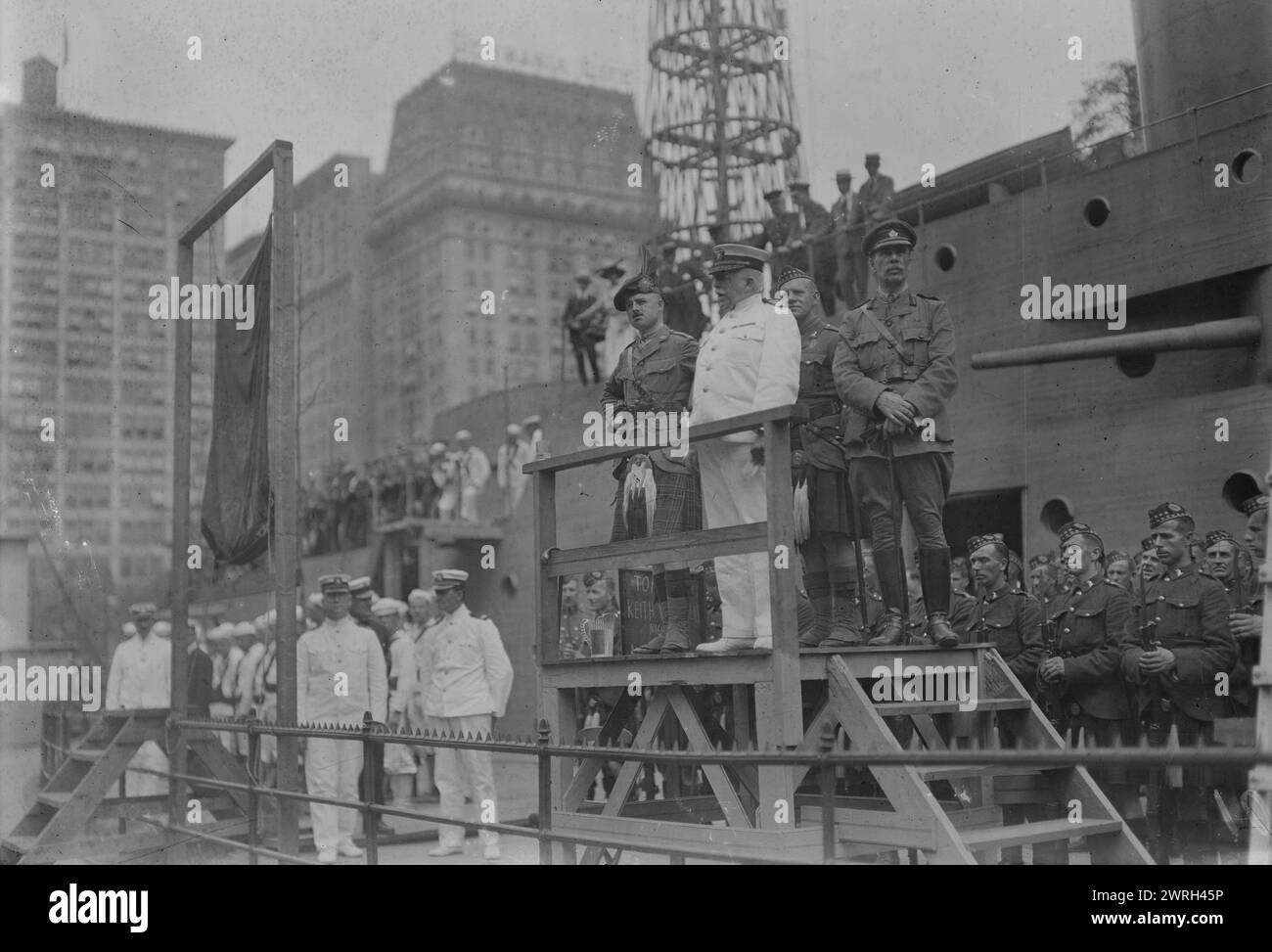 Il capitano Adams si rivolge alle reclute, luglio 1917. Il capitano Charles Albert Adams (1846-1929), un ufficiale della marina statunitense che servì come comandante della recluta degli Stati Uniti, un mockup di legno di una nave da battaglia costruita a Union Square, New York City dalla Marina per reclutare marinai e vendere obbligazioni Liberty durante la prima guerra mondiale Adams sta salutando le nuove reclute insieme ai soldati canadesi degli Highlander ("Kilties") che erano a New York nel luglio 1917 per assistere nel reclutamento. Foto Stock