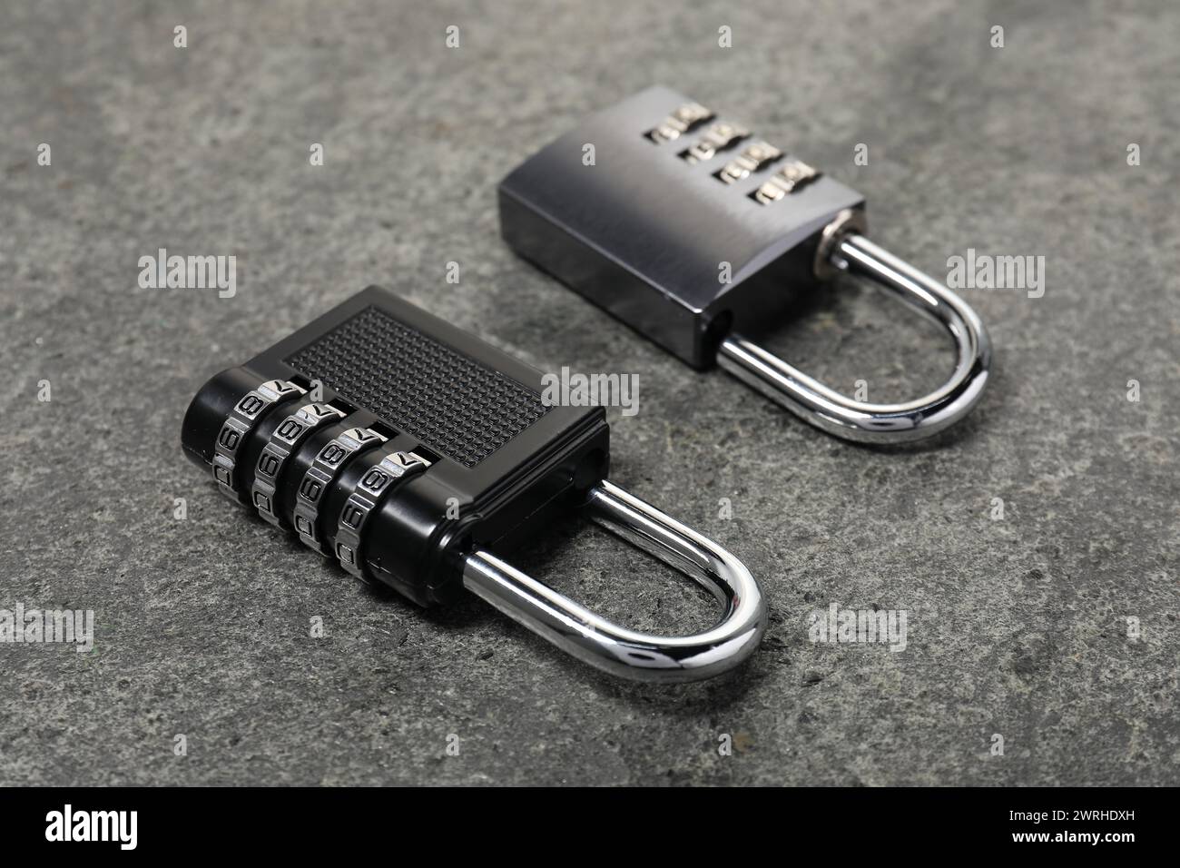 Lucchetti combinati in acciaio con serratura su tavolo in pietra grigia, primo piano Foto Stock
