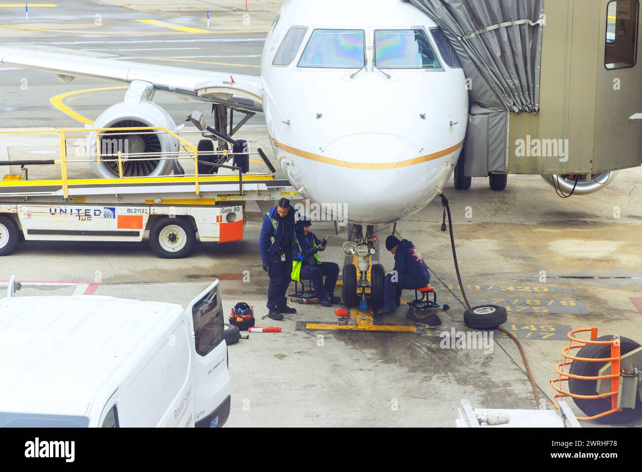30 ottobre 2023 EWR Newark NJ US United Airlines meccanici di manutenzione degli aeromobili al lavoro seduti sui suoi stalli sotto l'aereo Foto Stock