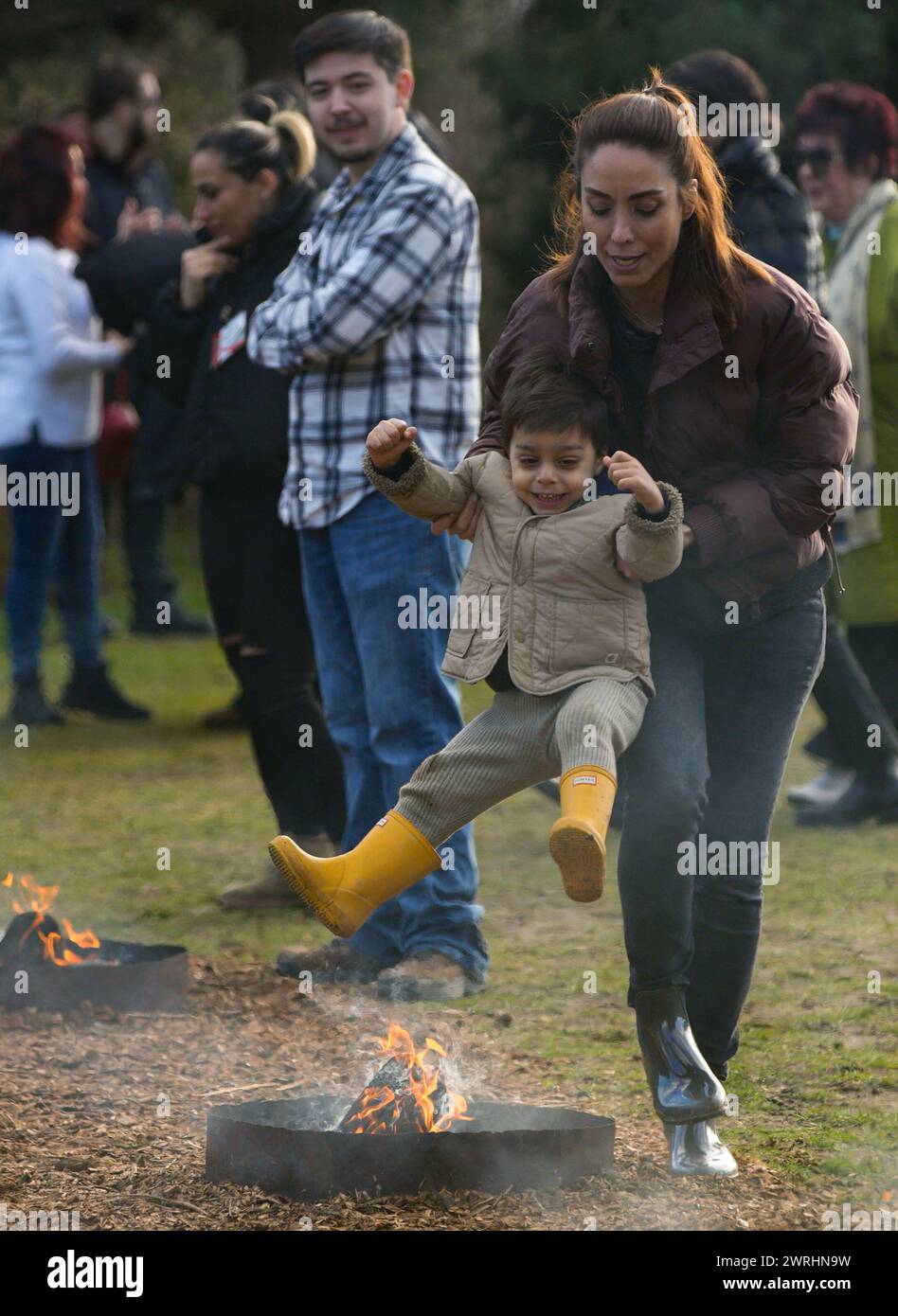 Vancouver, Canada. 12 marzo 2024. Le persone saltano sopra un falò durante un festival del fuoco all'Ambleside Park a West Vancouver, British Columbia, Canada, il 12 marzo 2024. Il festival si è tenuto dalla comunità iraniana locale per celebrare il prossimo Nowruz, il nuovo anno iraniano. Crediti: Liang Sen/Xinhua/Alamy Live News Foto Stock