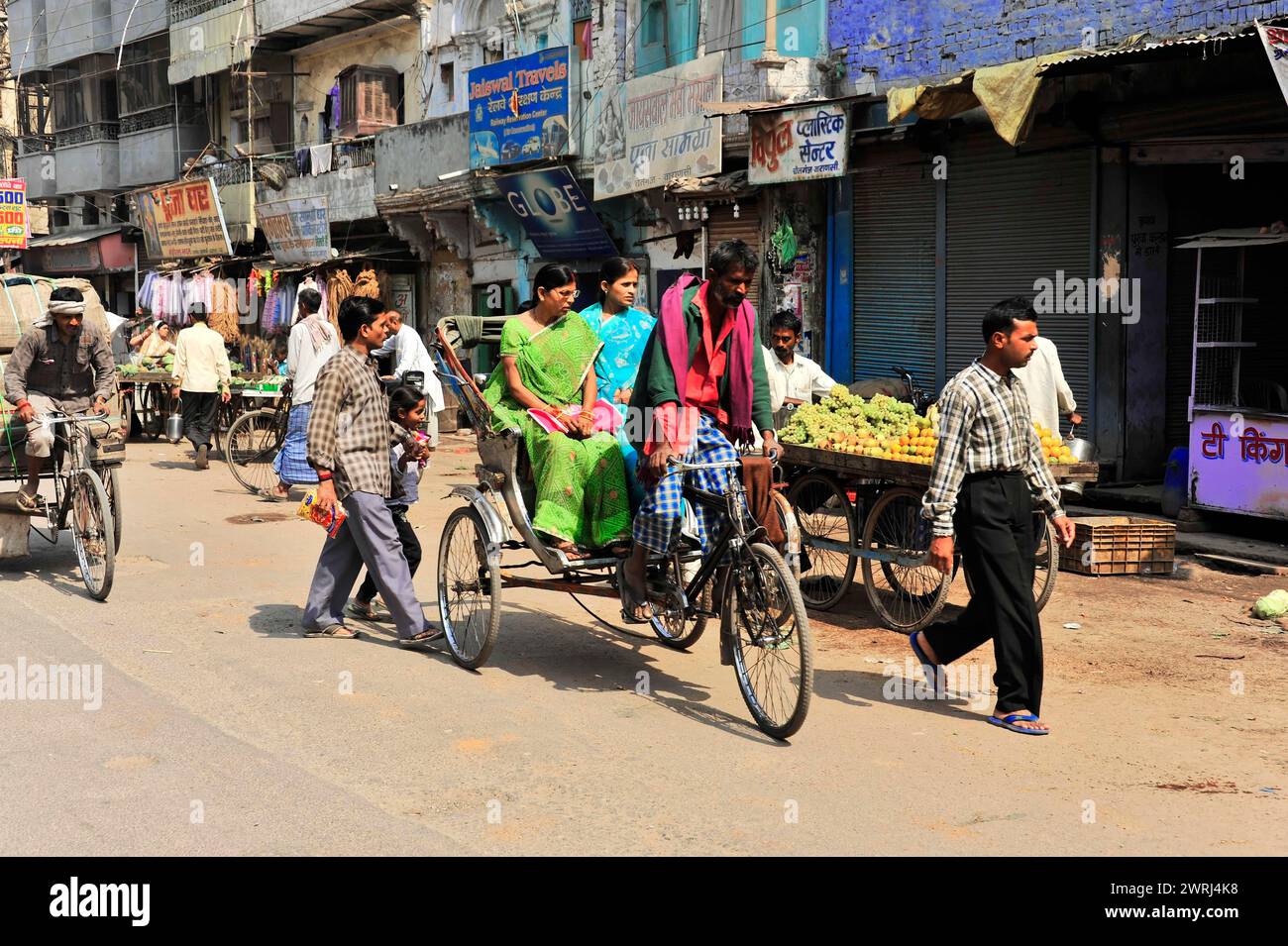 Persone in abito tradizionale che cavalcano in risciò in una strada della città, Varanasi, Uttar Pradesh, India Foto Stock