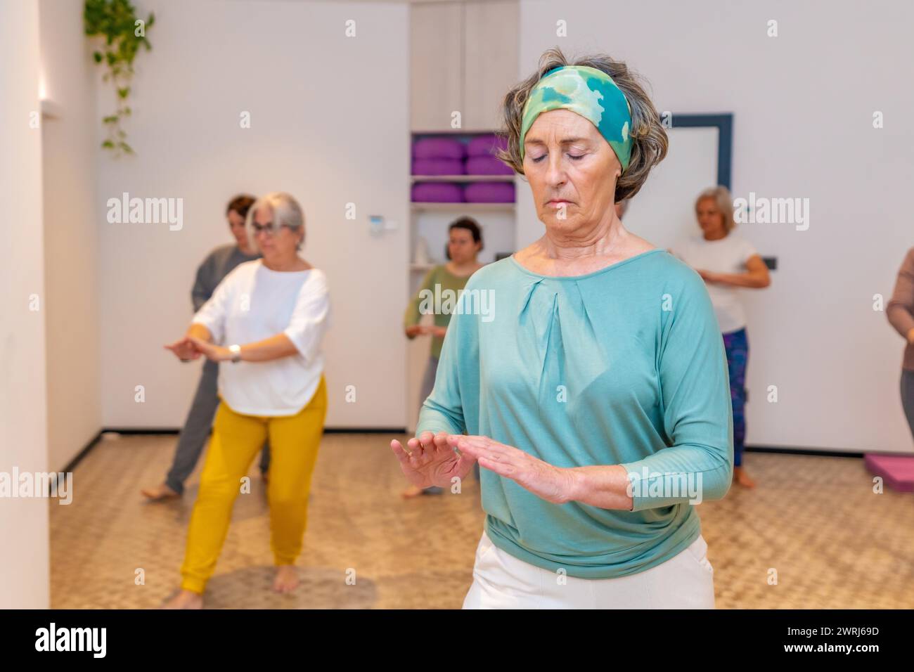 Donna concentrata che chiude gli occhi e respira durante l'esercizio fisico durante la classe qi gong Foto Stock