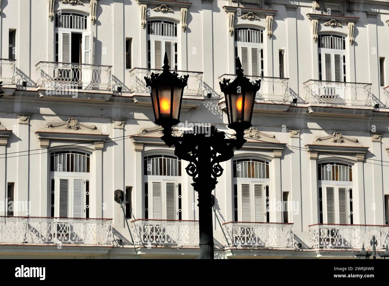 Architettura classica con facciate strutturate delle finestre e lampioni illuminati, Havana, Cuba, America centrale Foto Stock