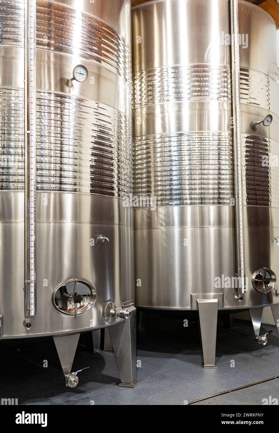 Vasche in acciaio inox lucide utilizzate per la fermentazione e l'invecchiamento del vino, che presentano una moderna tecnologia di vinificazione. Foto Stock
