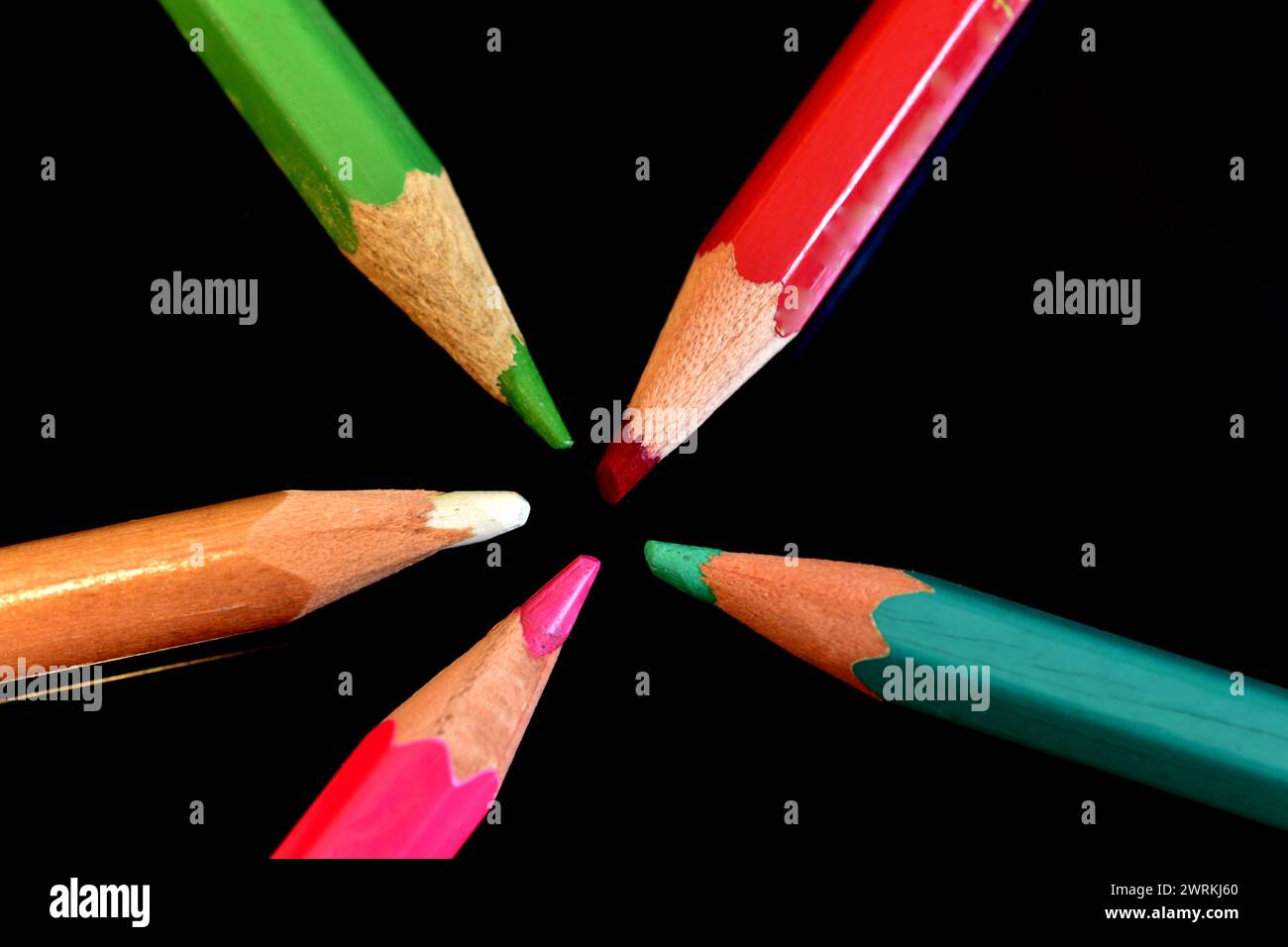 L'immagine mostra matite colorate pronte per l'uso, posizionate su uno sfondo scuro con i cavi al centro. Foto Stock