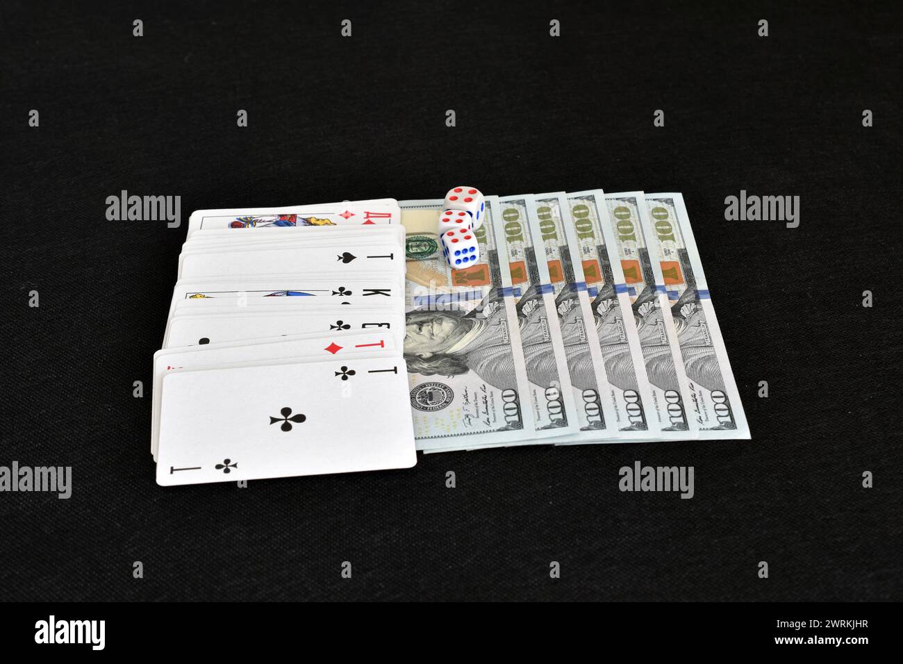 Un mazzo di carte giace in cima ai soldi disposti in fila sul tavolo da gioco. Foto Stock