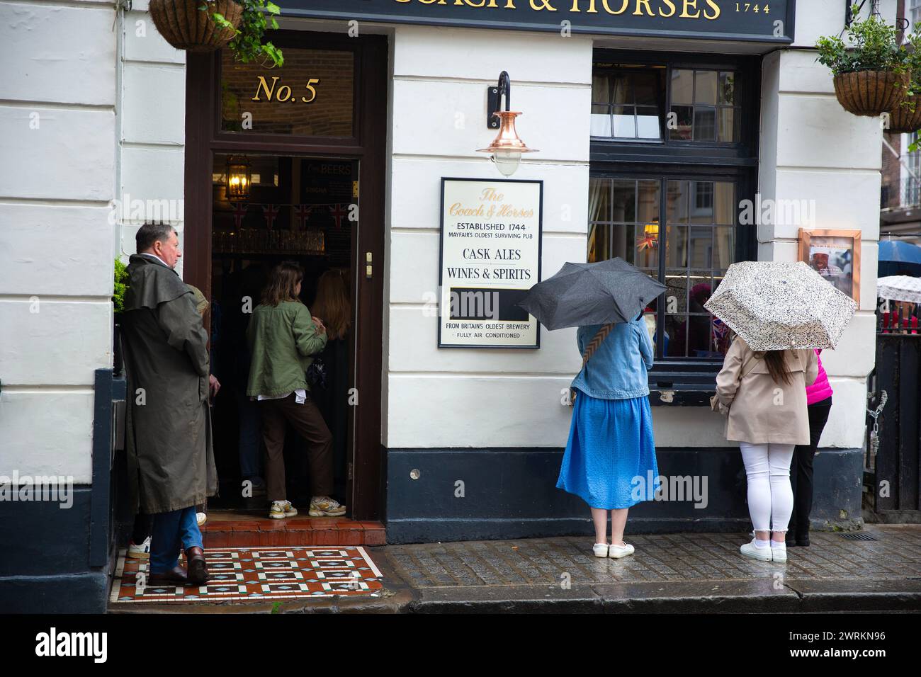 La gente guarda l'incoronazione di re Carlo III sullo schermo in un pub nel centro di Londra. Foto Stock