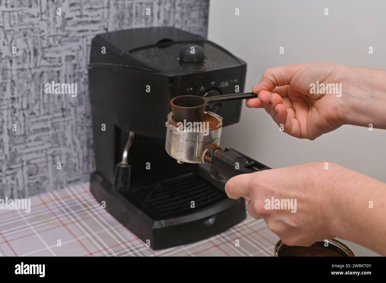 le mani delle donne versano il caffè nella macchina per il caffè Foto Stock
