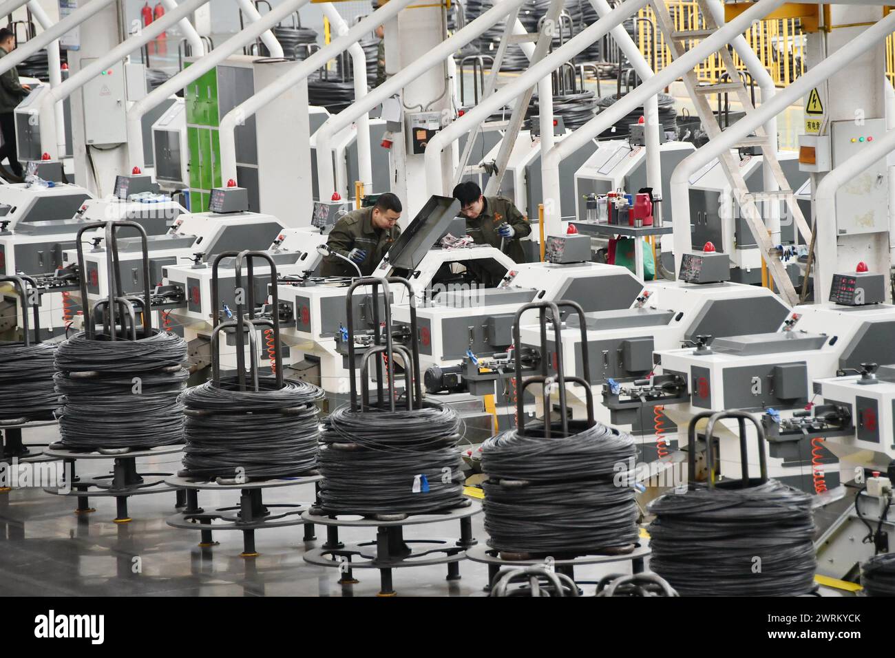 HANDAN, CINA - 12 MARZO 2024 - i lavoratori stanno controllando il funzionamento delle apparecchiature in un'officina di produzione digitale intelligente presso un'azienda produttrice di hardware Foto Stock