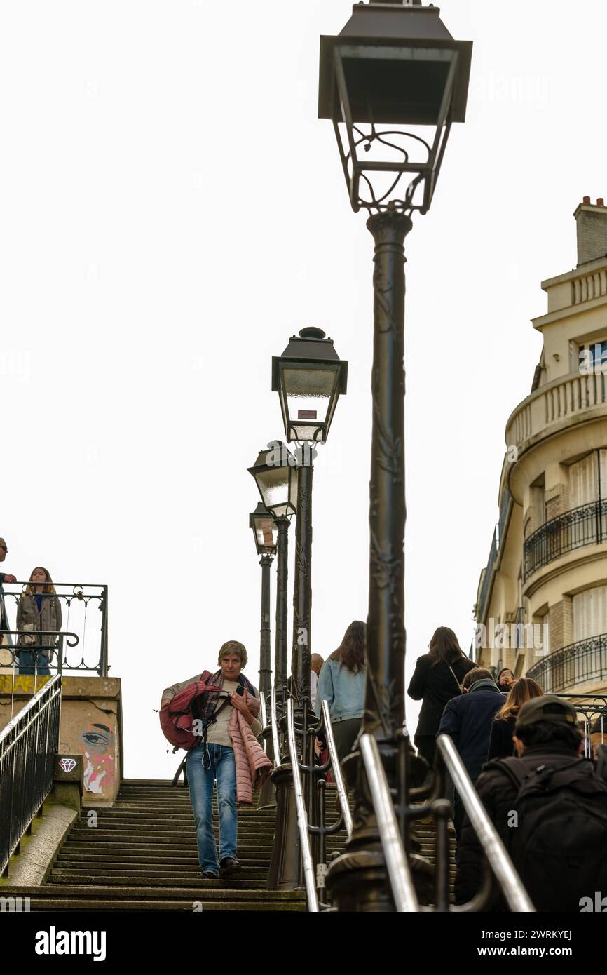 Parigi, Francia - 17 febbraio 2024: Veduta dei turisti che camminano su e giù per le pittoresche scale con lanterne parigine nel Montmartre Parigi Foto Stock