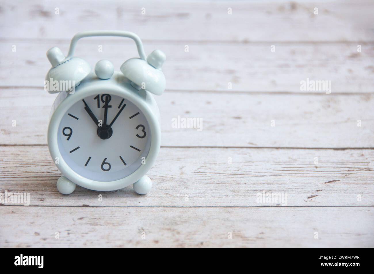Sveglia bianca con puntamento alle 11:00 su un tavolo di legno. Copia concetto di spazio e tempo. Foto Stock