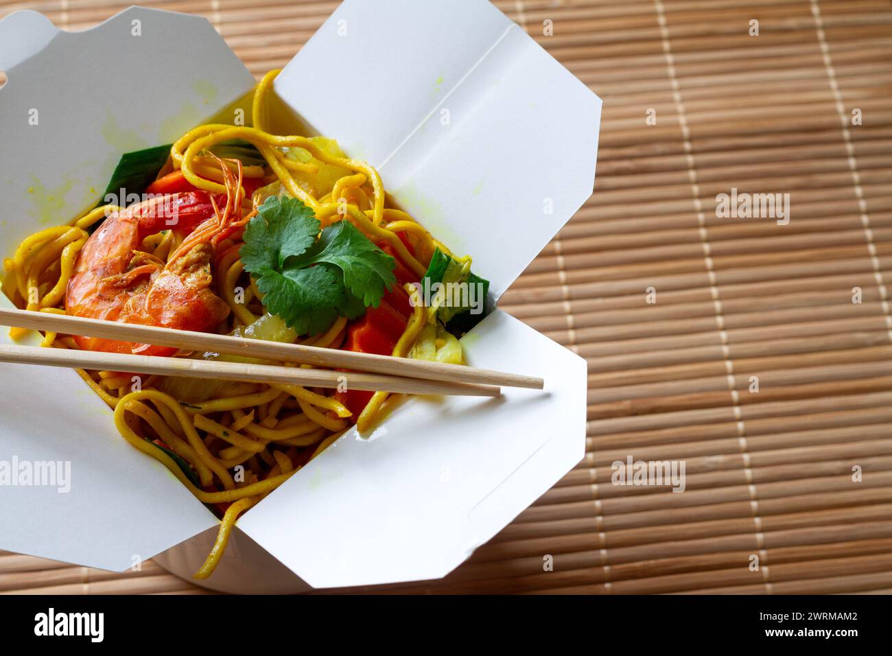 Spaghetti cinesi con gamberetti e verdure in scatola su tappetino in bambù. Cucina cinese Foto Stock