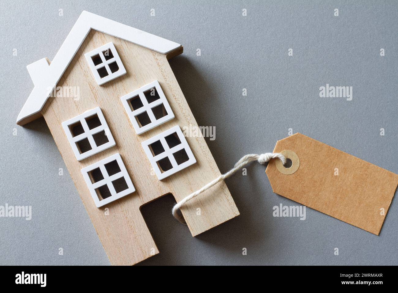 Modello in miniatura di casa in legno con etichetta, concetto di vendita, acquisto o affitto di immobili Foto Stock