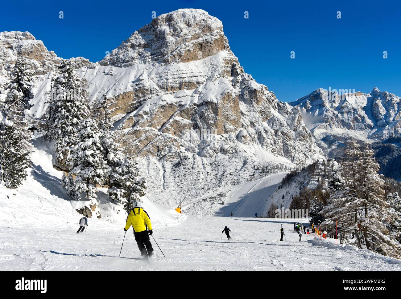 Sciatori su una pista nella località di sport invernali di Colfosco ai piedi della cima Sassongher nel comprensorio sciistico dell'alta Badia, Dolomiti, alto Adige, Italia Foto Stock