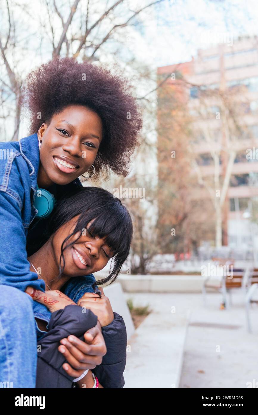 Catturate in un momento spontaneo di gioia, due sorelle condividono un profondo abbraccio, i loro sorrisi irradiano affetto e felicità genuini Foto Stock