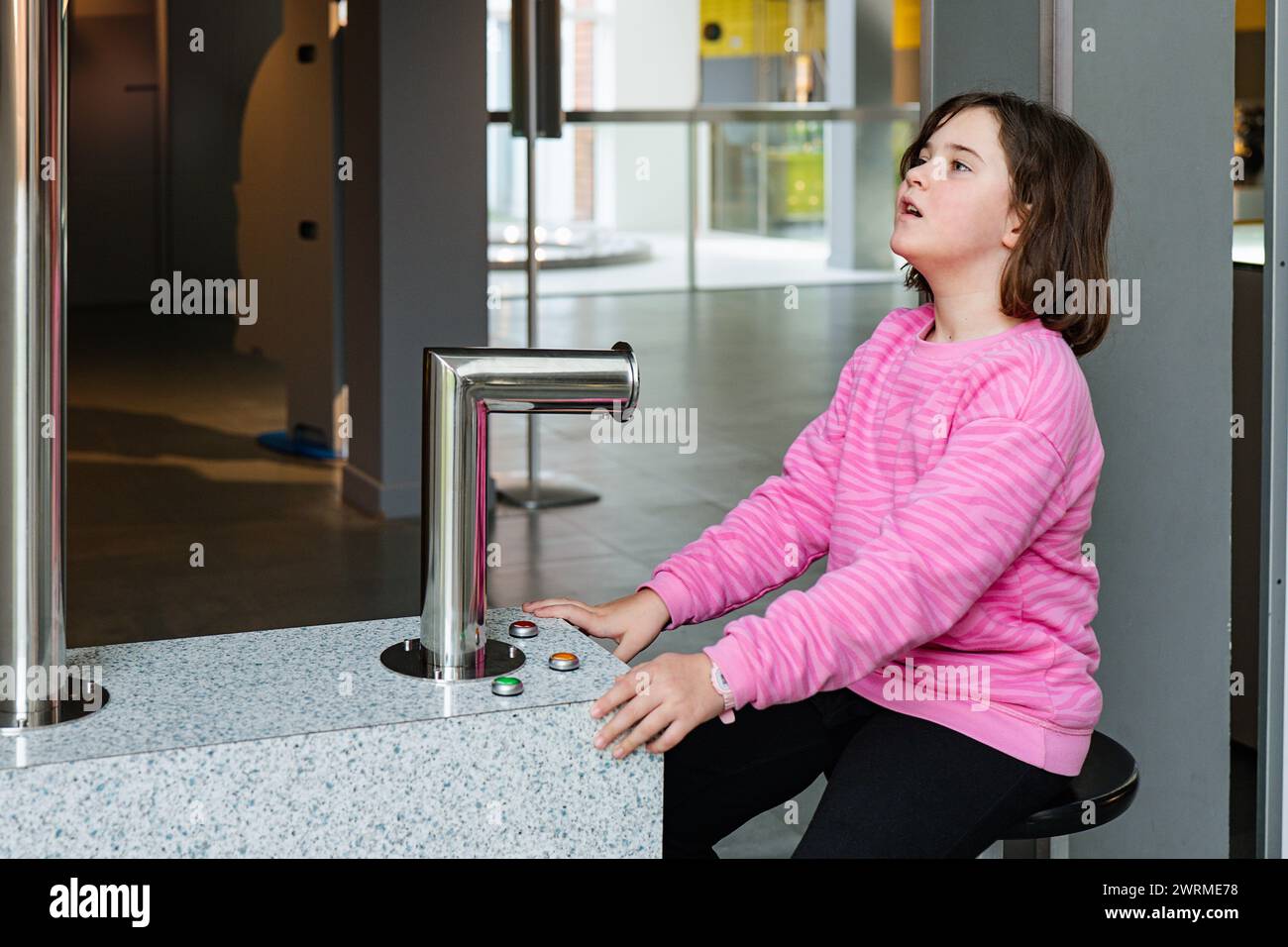 Una ragazza gioiosa interagisce con una mostra pratica di scienze, mostrando la natura interattiva dei moderni musei per bambini. Foto Stock