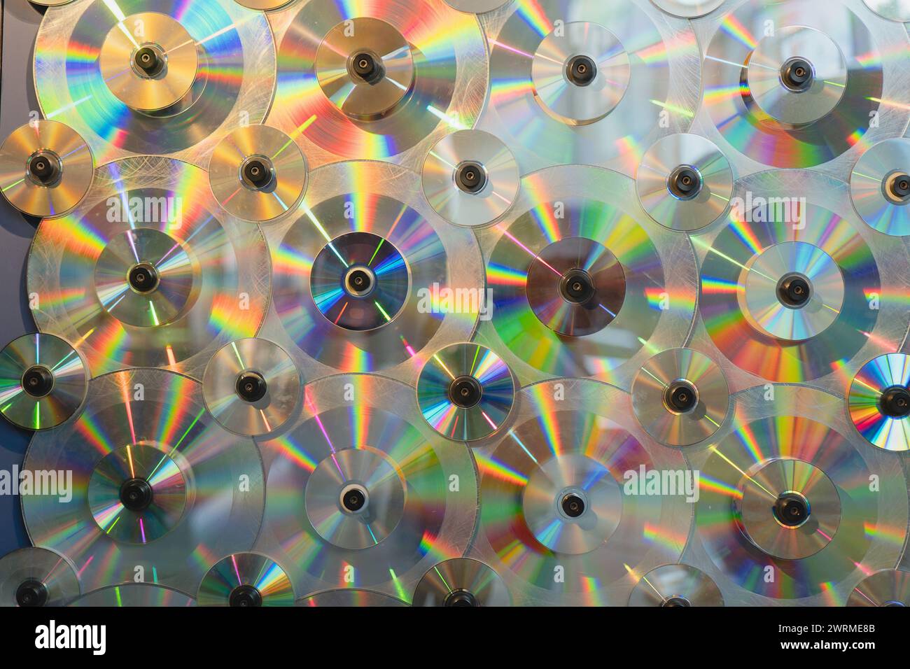 Un brillante display di sequenze luminose rifrangenti attraverso una parete di compact disc disposti. Foto Stock
