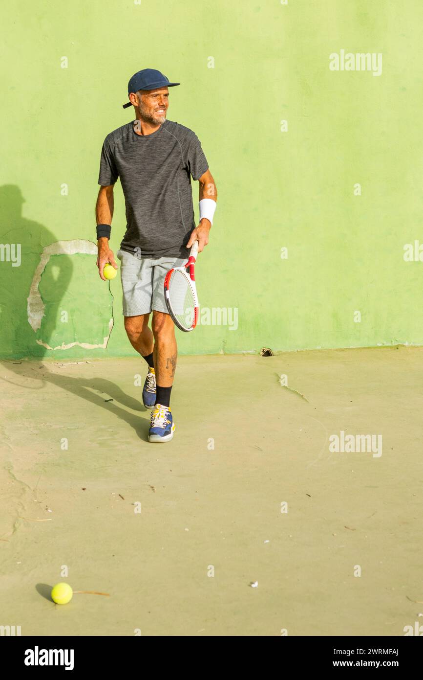 Uomo anziano che gioca a tennis in una giornata di sole. Foto Stock