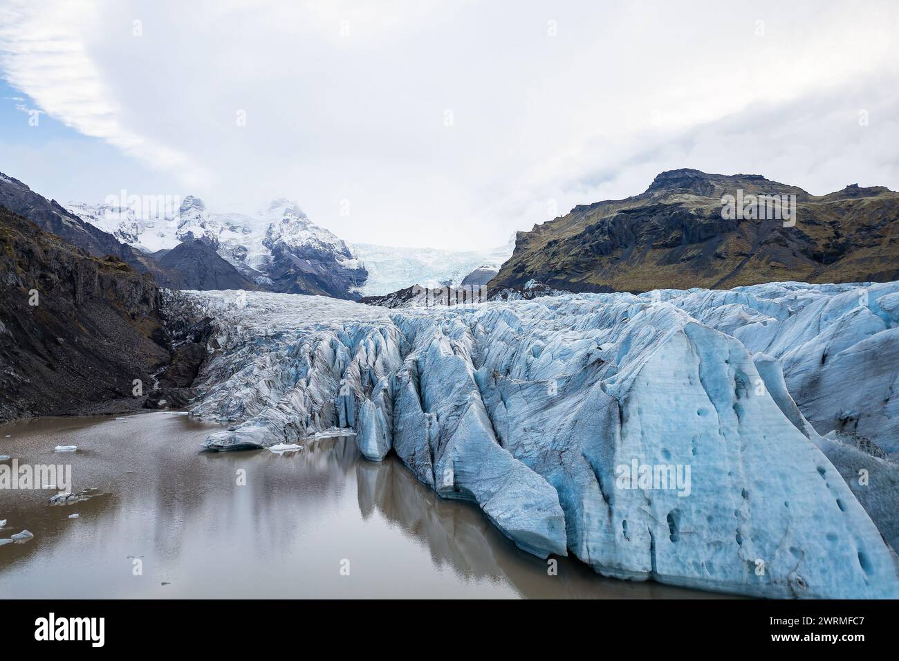 L'ampio ghiacciaio Vatnajokull si estende in lontananza, fiancheggiato dalle aspre montagne islandesi e riflesso nelle calme acque glaciali Foto Stock