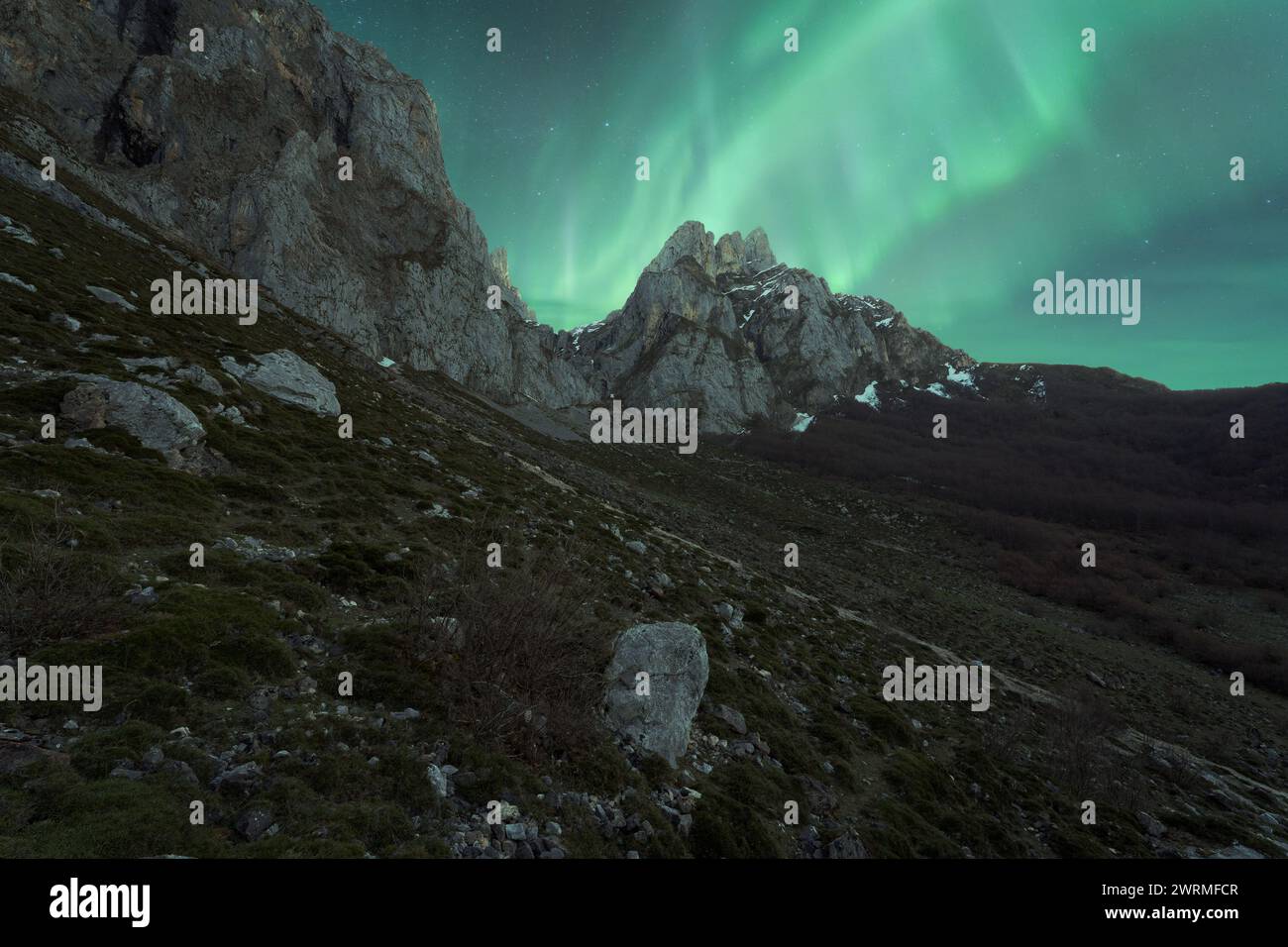 Le maestose aurore danzano sulle aspre montagne in un tranquillo paesaggio notturno islandese. Foto Stock