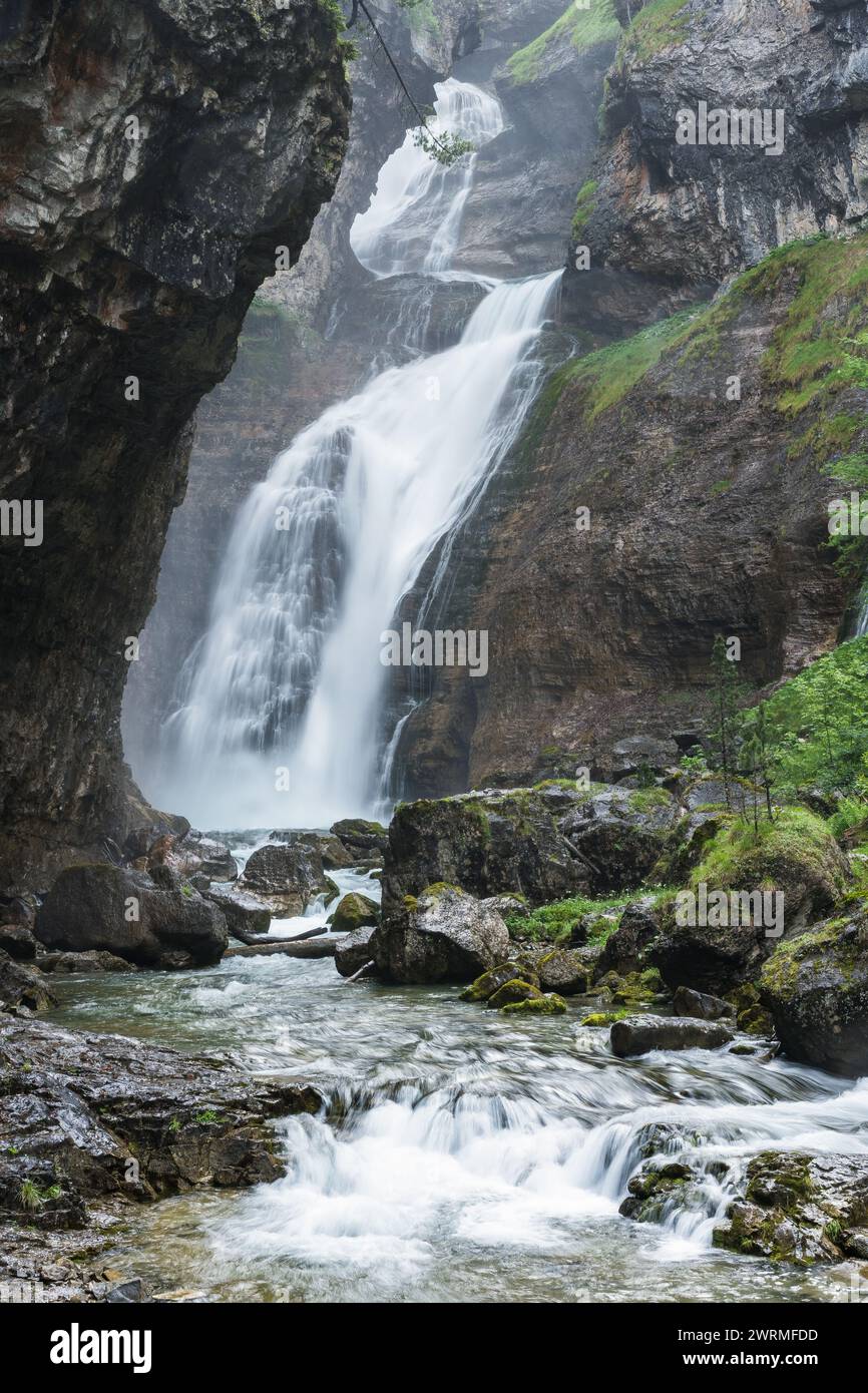 La Valle d'Ordesa svela il suo splendore con una cascata a più livelli circondata da aspre scogliere e vegetazione lussureggiante Foto Stock