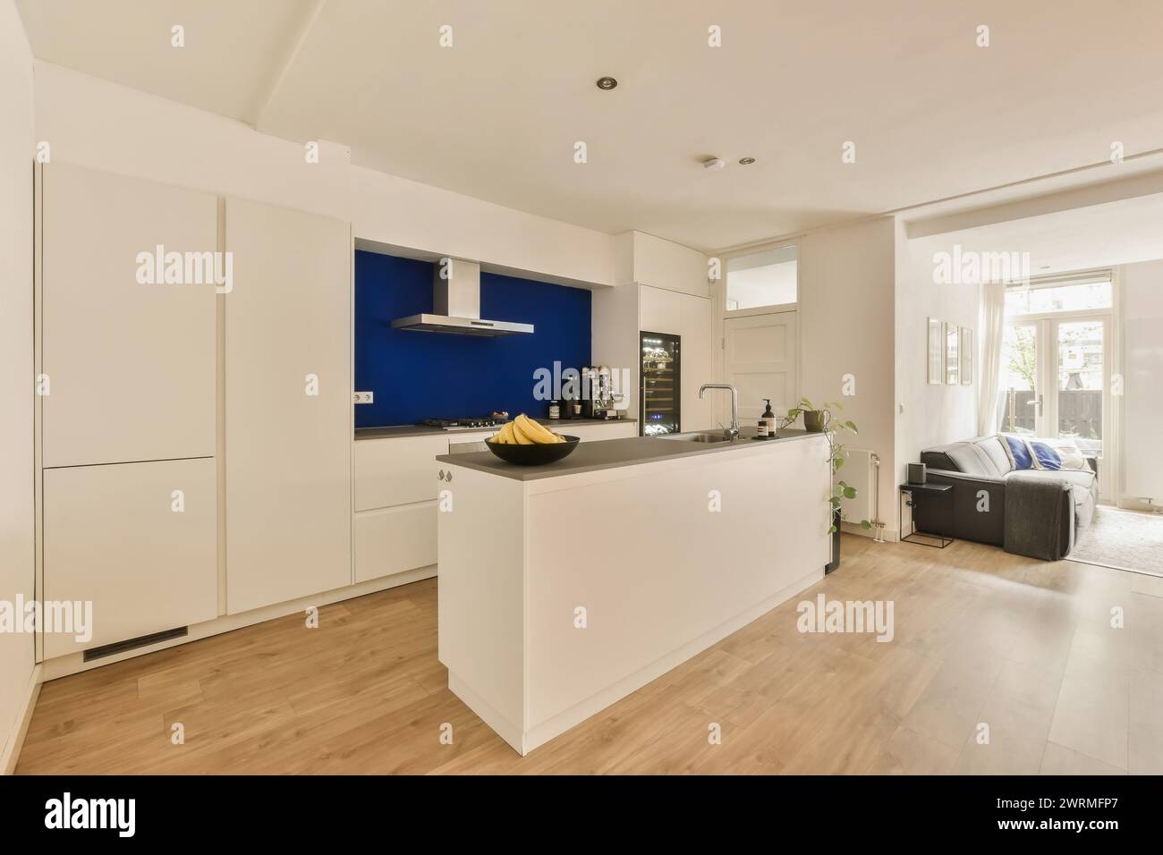 una cucina con armadi bianchi e una parete d'accento blu Foto Stock