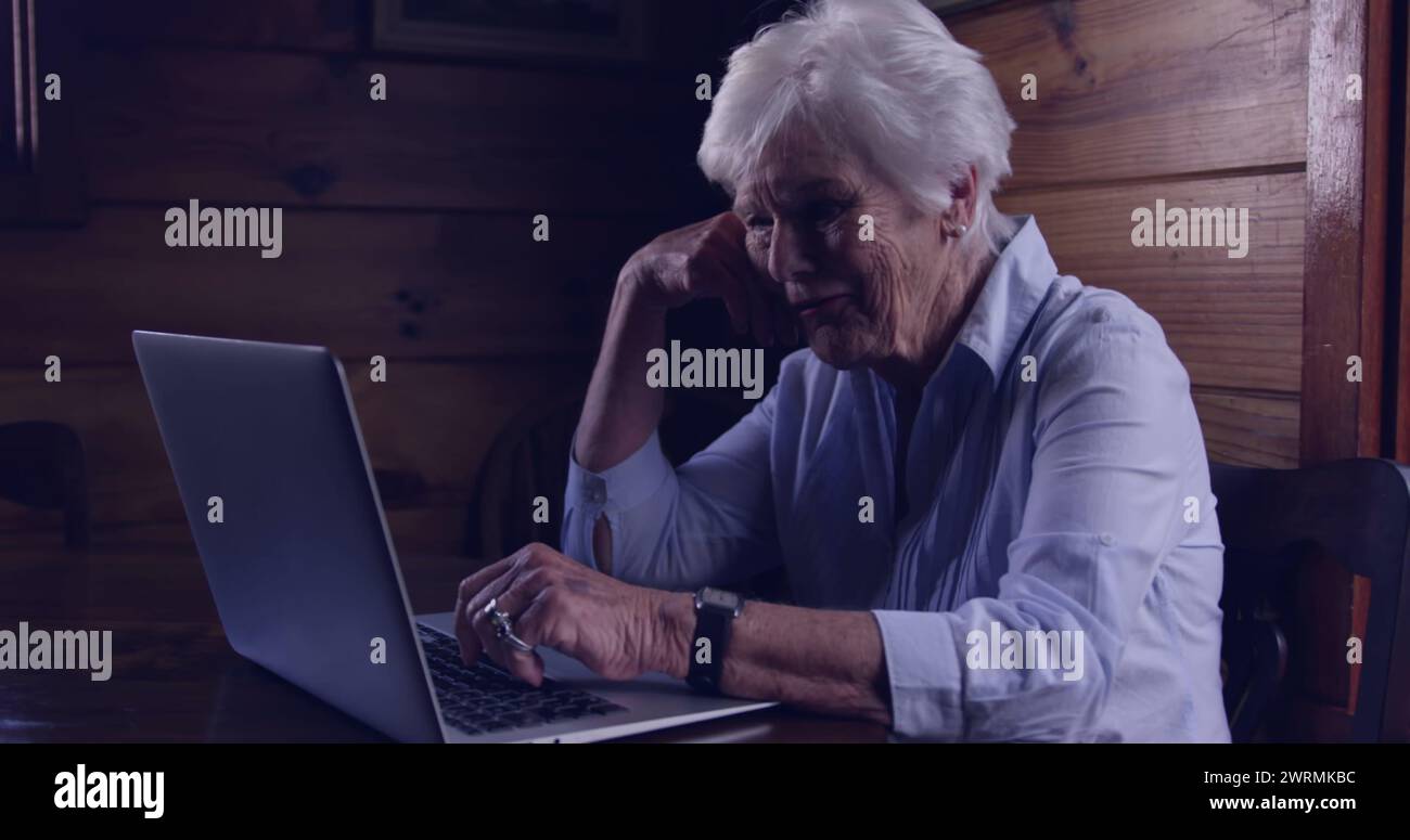 La donna caucasica anziana si concentra sul suo notebook a casa Foto Stock