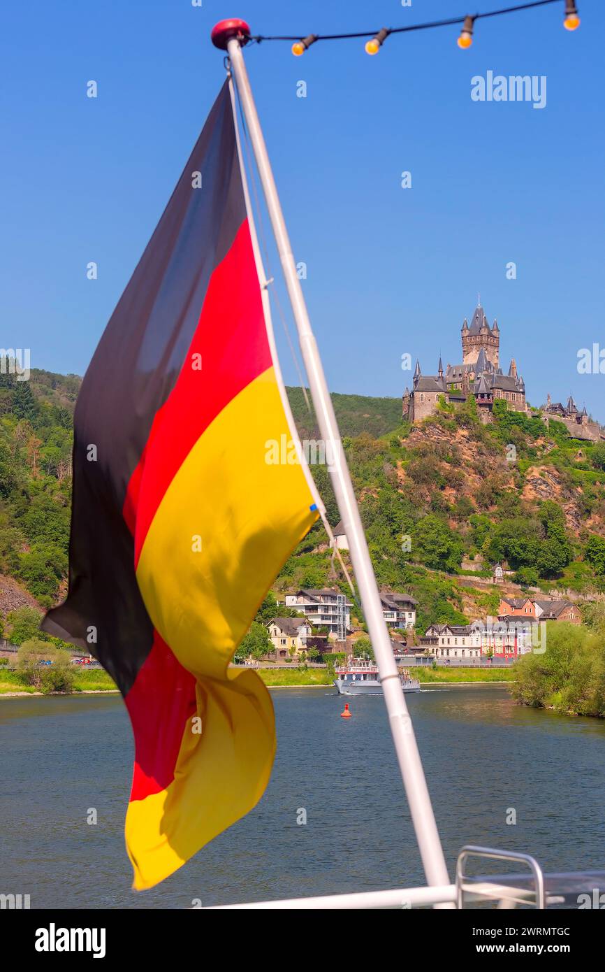 La bandiera tedesca sventola sullo sfondo del castello di Reichsburg, Cochem, Germania Foto Stock