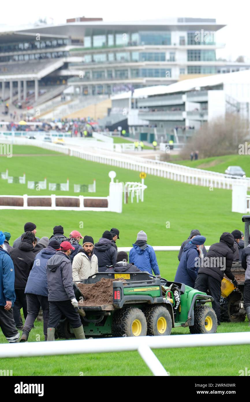 Ippodromo di Cheltenham, Gloucestershire Regno Unito - mercoledì 13 marzo 2024 - personale a terra che controlla la superficie del tappeto erboso dell'ippodromo e riempie i fori nell'erba prima dell'inizio del secondo giorno di questo anno Cheltenham Festival. Foto Steven May / Alamy Live News Foto Stock