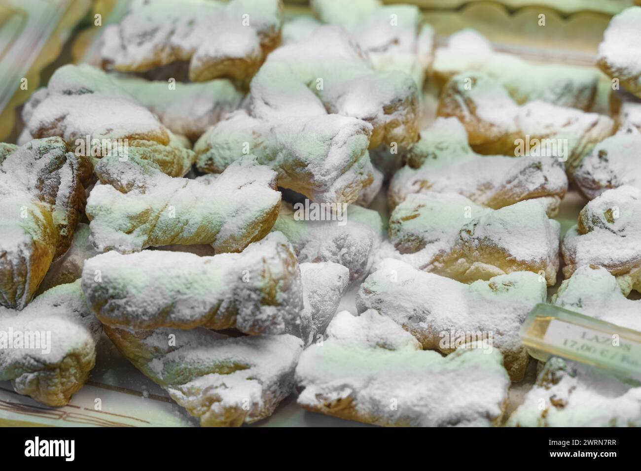 Un vassoio ripieno di pasticcini assortiti, come croissant e muffin, viene mostrato da vicino, ognuno delicatamente coperto da una spolverata di zucchero a velo. Foto Stock