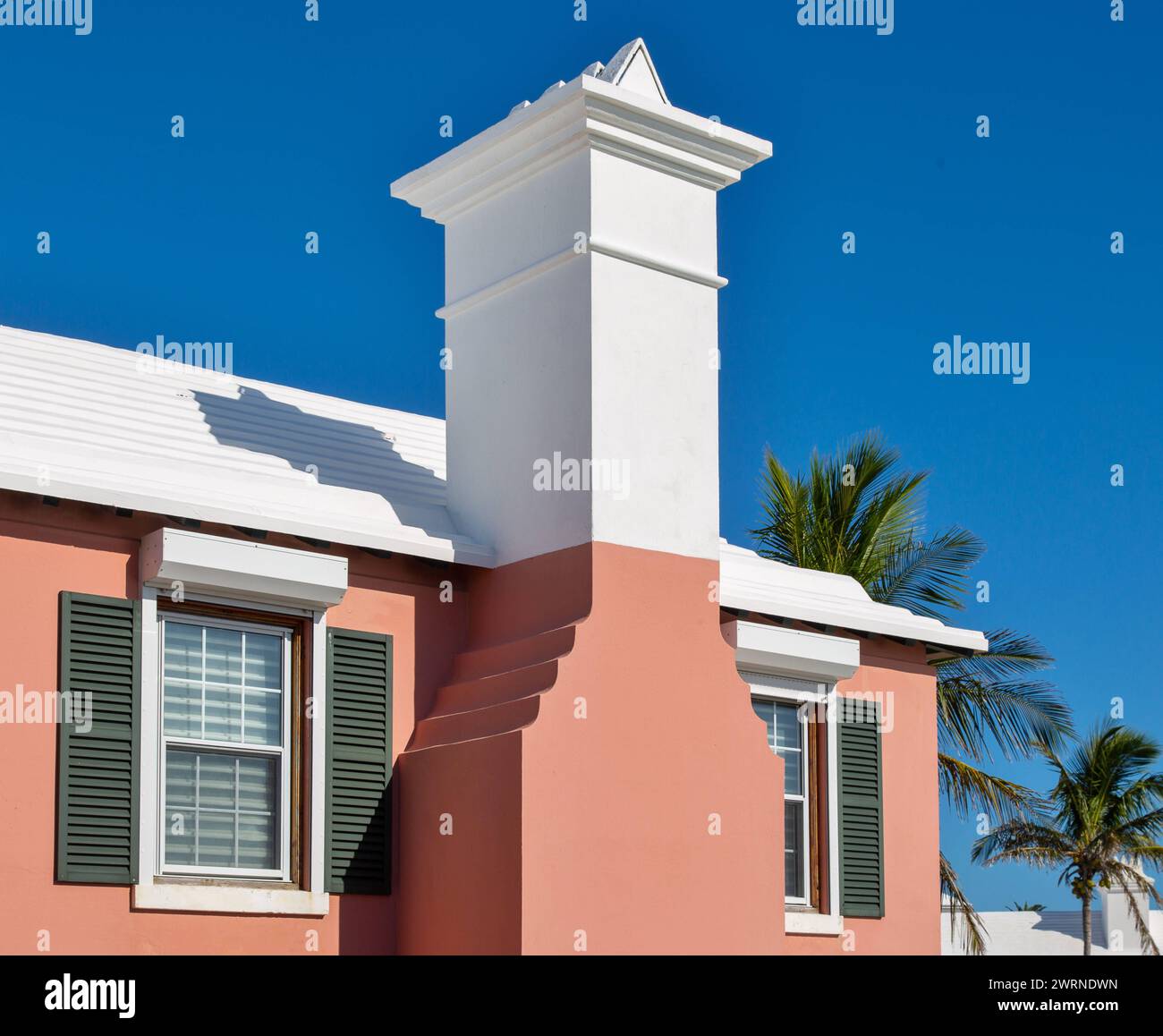 Tipica architettura delle Bermuda, edificio dipinto in colori pastello, con tetto bianco a gradini progettato per catturare l'acqua piovana per lo stoccaggio in vasche sotterranee Foto Stock