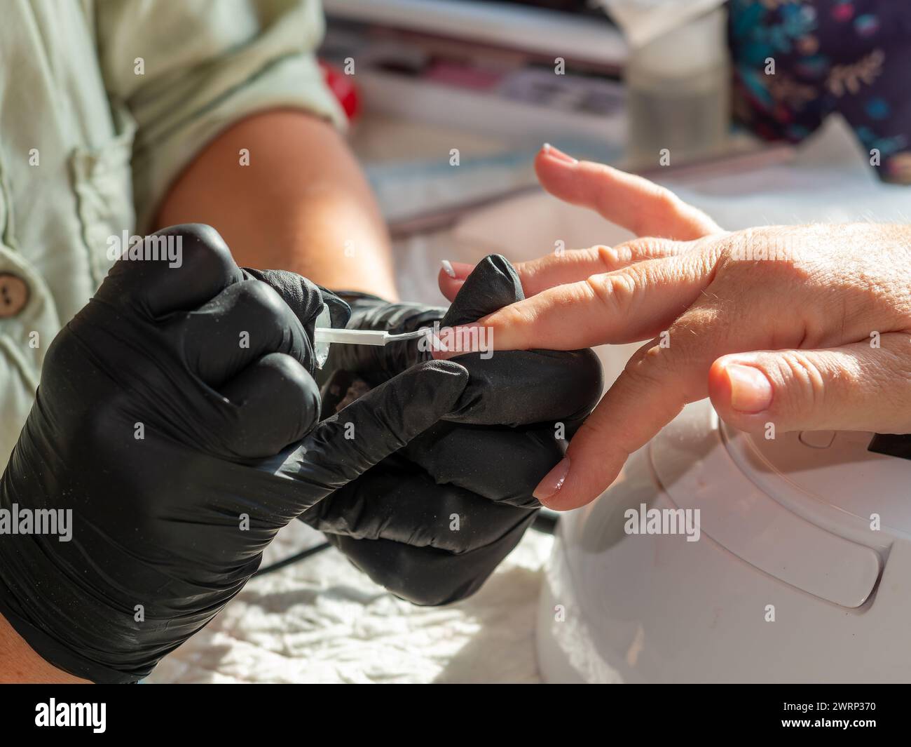 Donna che fa la manicure applicando lo smalto francese per la pittura permanente delle unghie Foto Stock