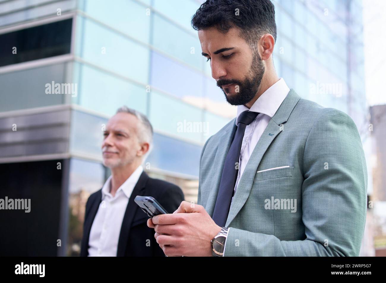 Si adatta bene al giovane uomo d'affari che scrive, concentrandosi sul telefono fuori dall'edificio degli uffici. Copia spazio. Foto Stock