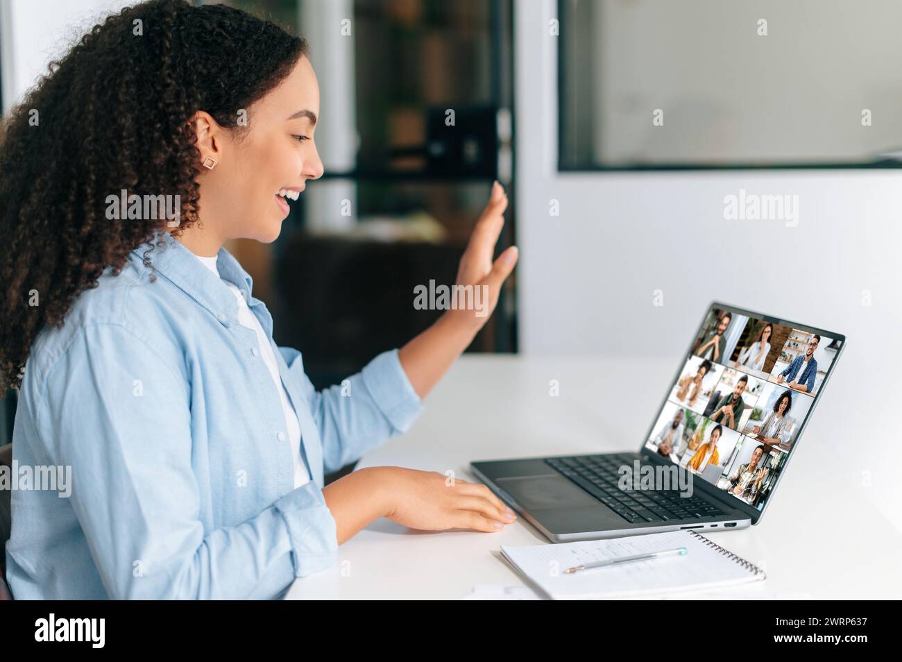 Videochiamata, brainstorming di gruppo. Imprenditrice brasiliana o ispanica, team leader, seduta sul posto di lavoro di fronte a un laptop, in videoconferenza online con team multirazziale Foto Stock