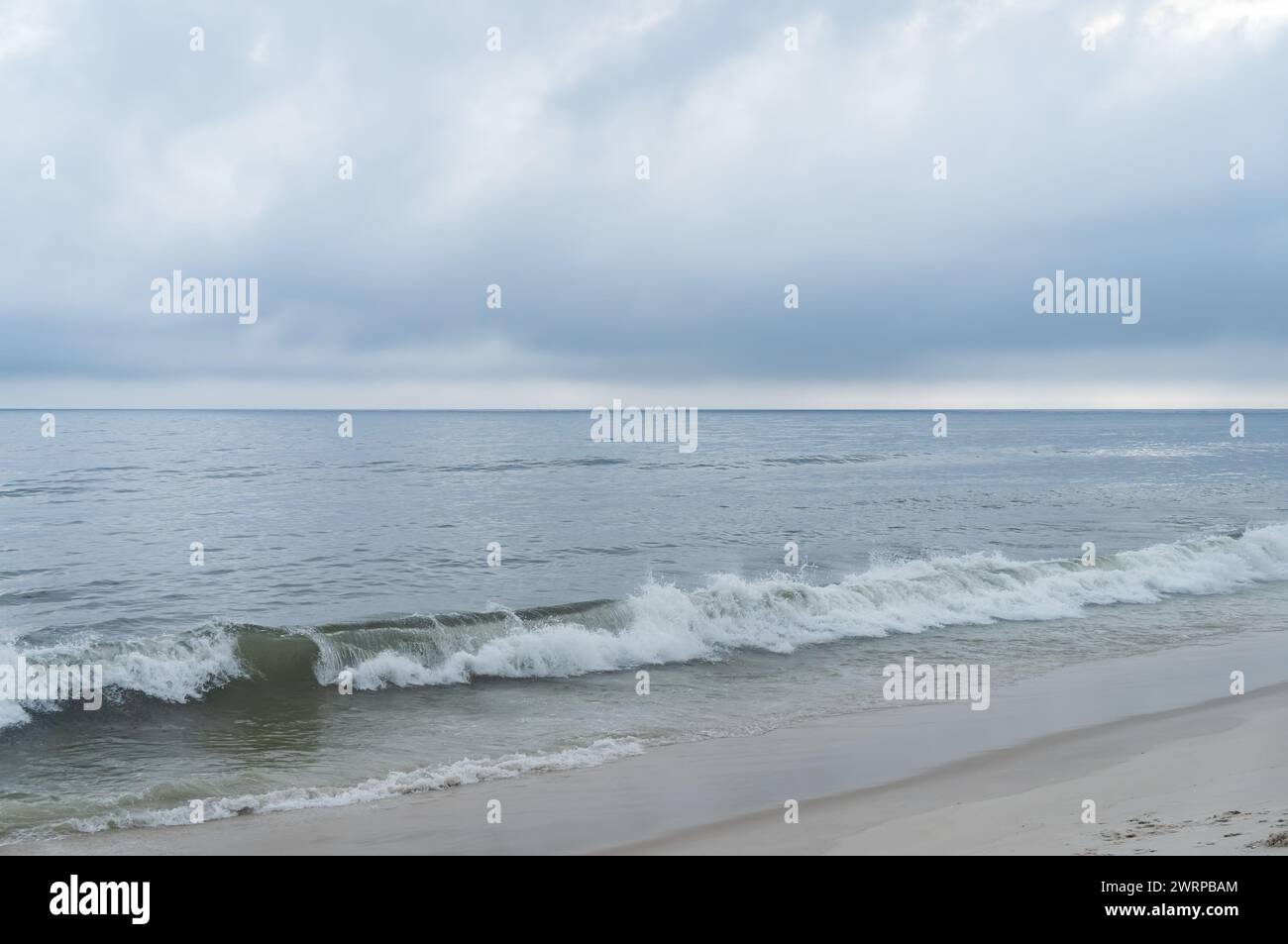 Dolci onde oceaniche dalle acque blu dell'Oceano Atlantico che si infrangono e colpiscono le sabbie bianche della spiaggia di Praia Seca sotto il cielo nuvoloso pomeridiano estivo. Foto Stock