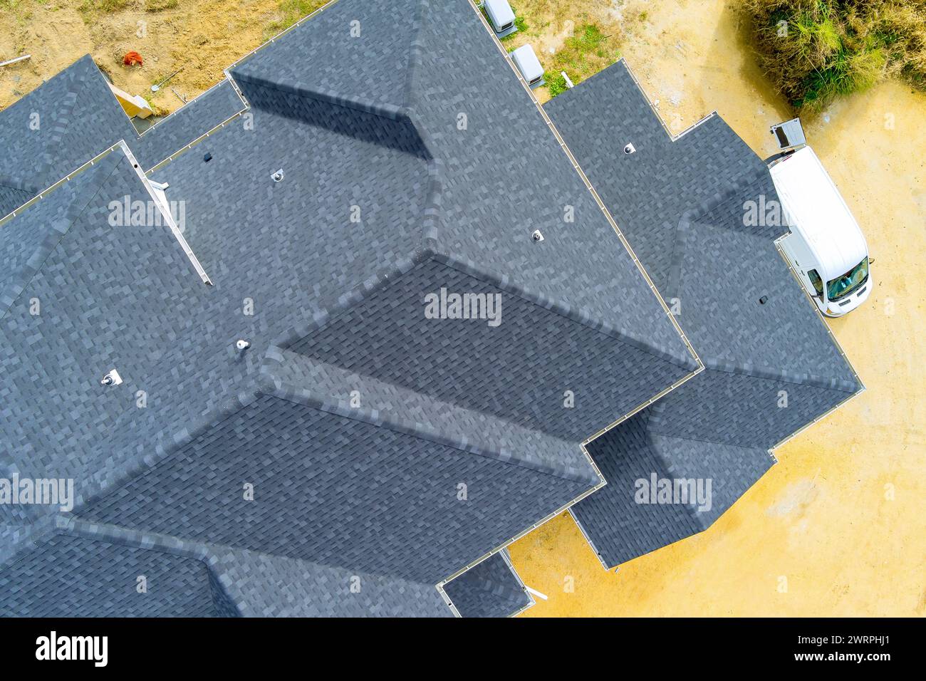 Sono presenti tegole di asfalto che coprono il tetto di una casa di nuova costruzione Foto Stock
