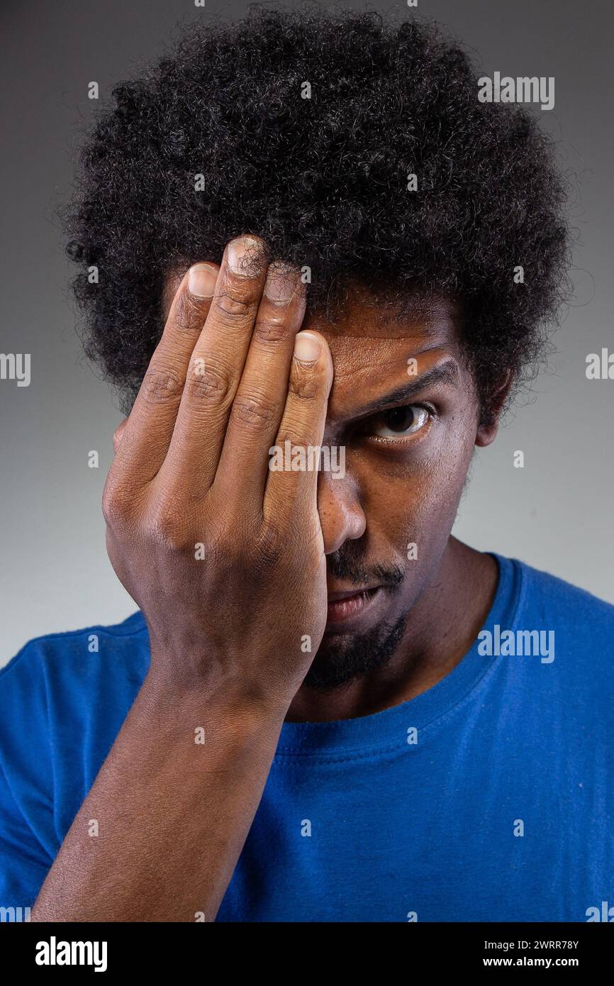 Un'immagine intensa che cattura un uomo che preme la mano contro la fronte, probabilmente indicando un affaticamento oculare, un'emicrania o una concentrazione profonda Foto Stock