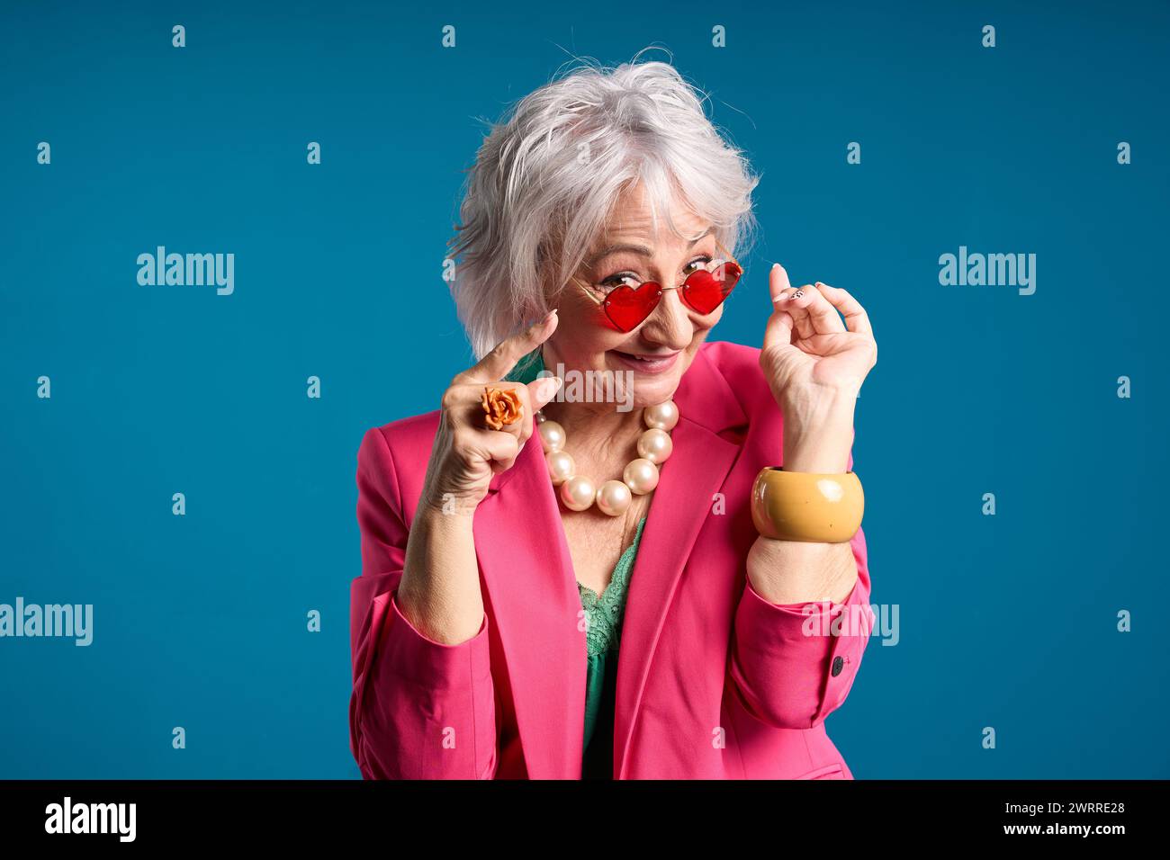 Giocosa signora anziana in occhiali da sole a forma di cuore che si avvolgono Foto Stock