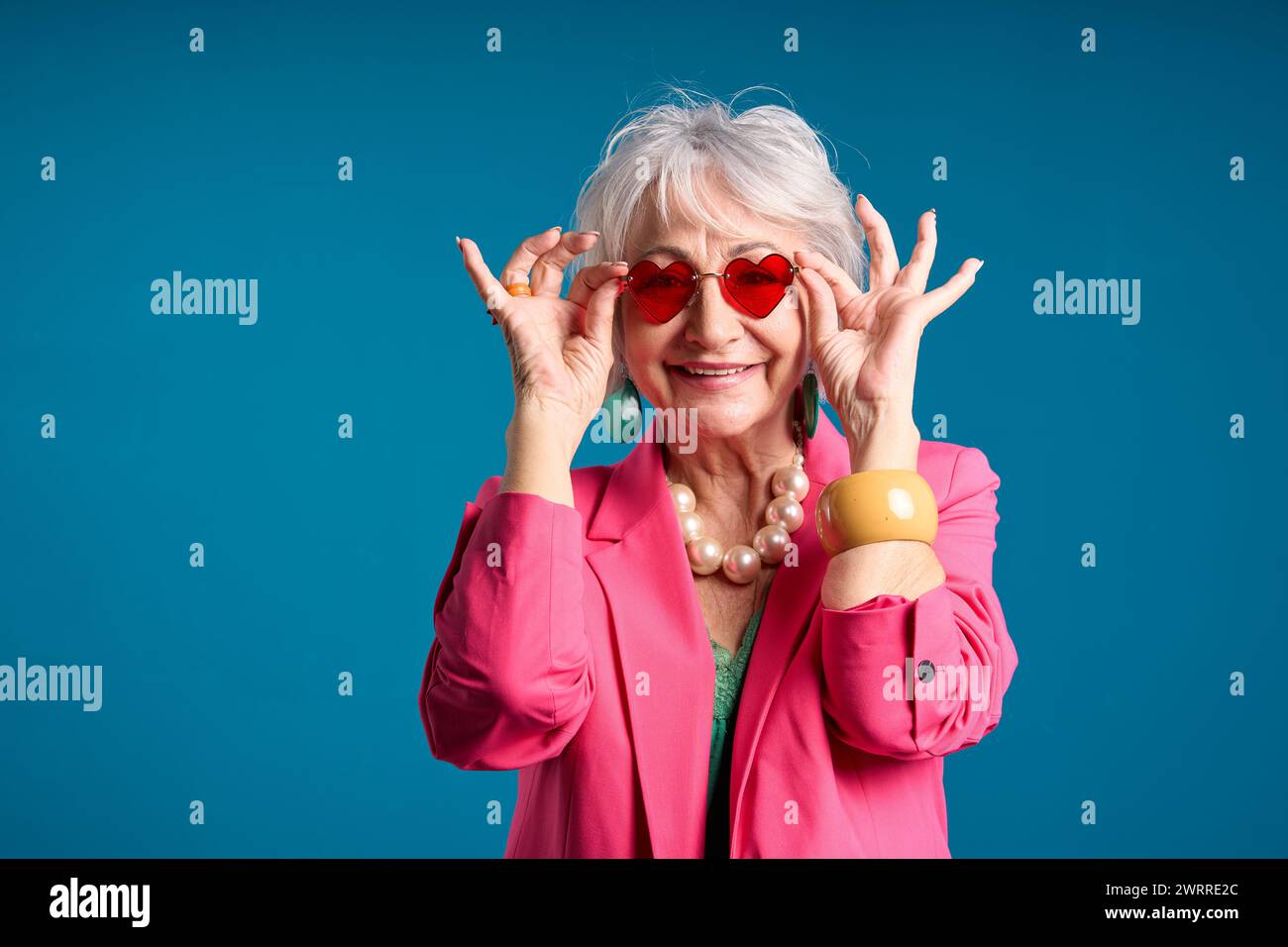 Donna anziana alla moda con occhiali da sole a forma di cuore Foto Stock