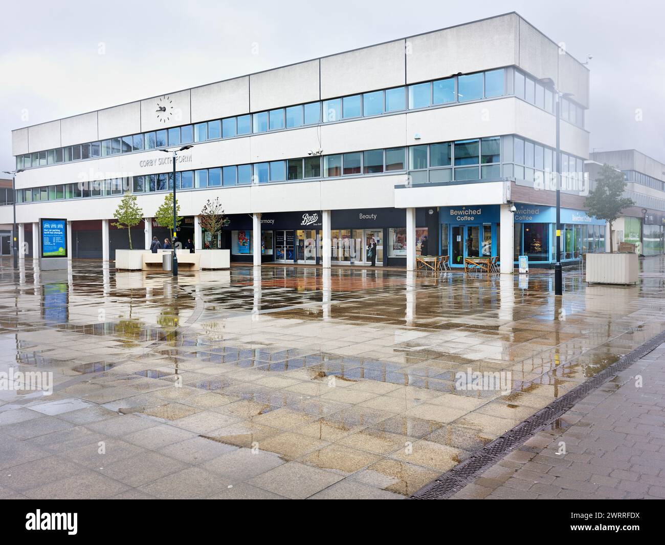Sesto college al centro commerciale di Corby in una giornata invernale piovosa, marzo 2024. Foto Stock