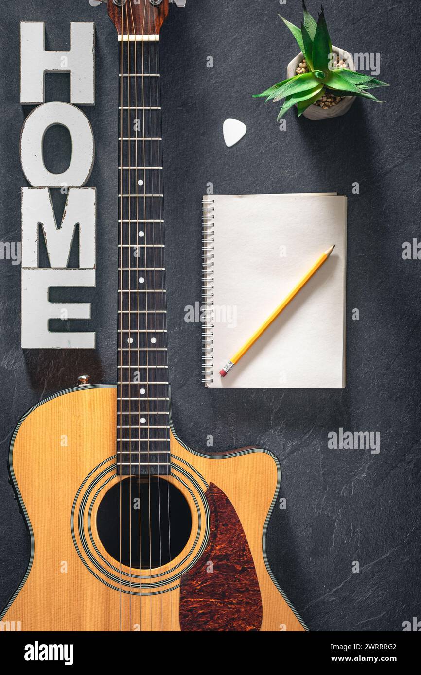 Chitarra acustica, blocco note e parola decorativa Home, vista dall'alto. Foto Stock