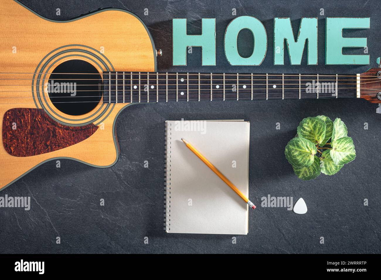 Chitarra acustica, blocco note e parola decorativa Home, vista dall'alto. Foto Stock