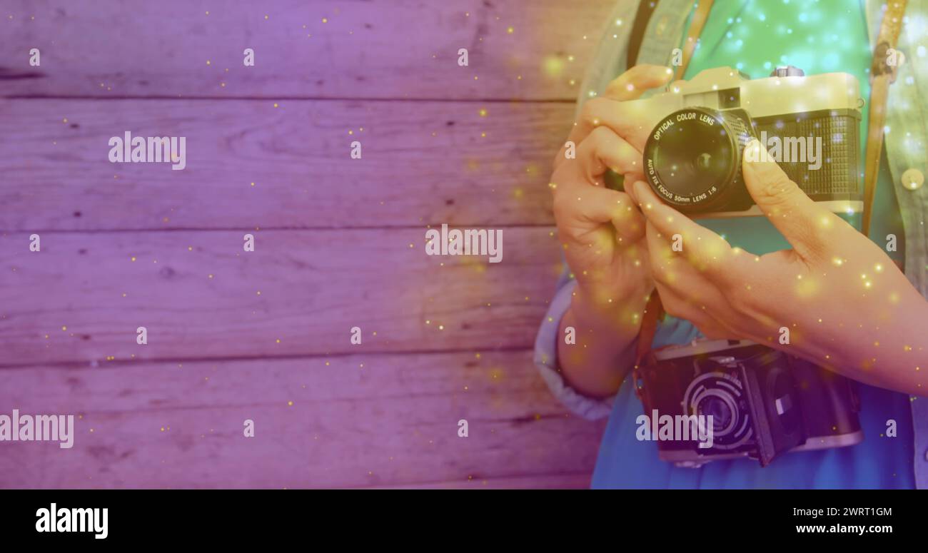 Si illumina contro la parte centrale di una fotografa che tiene in mano la sua fotocamera digitale Foto Stock