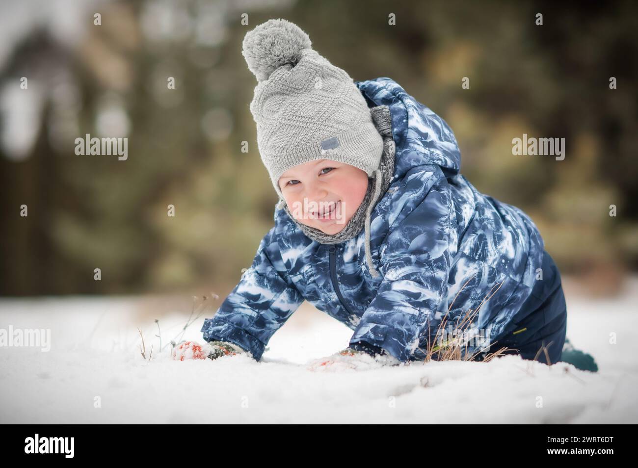 Adorabile bambino che ride giocando all'aperto sulla neve durante la bella giornata invernale. Bambino che esplora la natura. Attività invernali per bambini piccoli Foto Stock