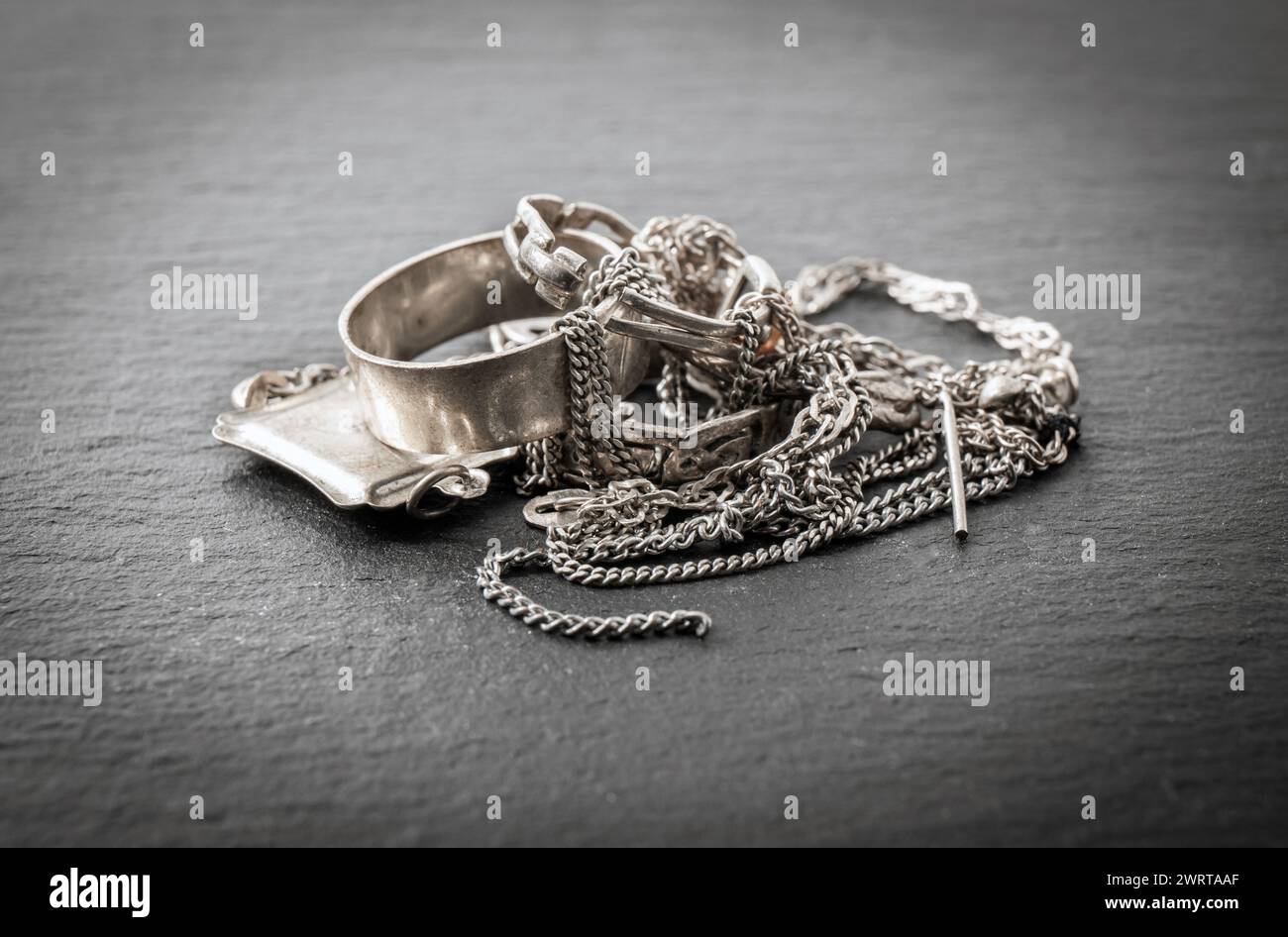 Pile di vecchi rottami in argento, gioielli, anelli, ciondoli, collane a catena, orecchini. Concetto di riciclaggio degli oggetti in argento. Foto Stock