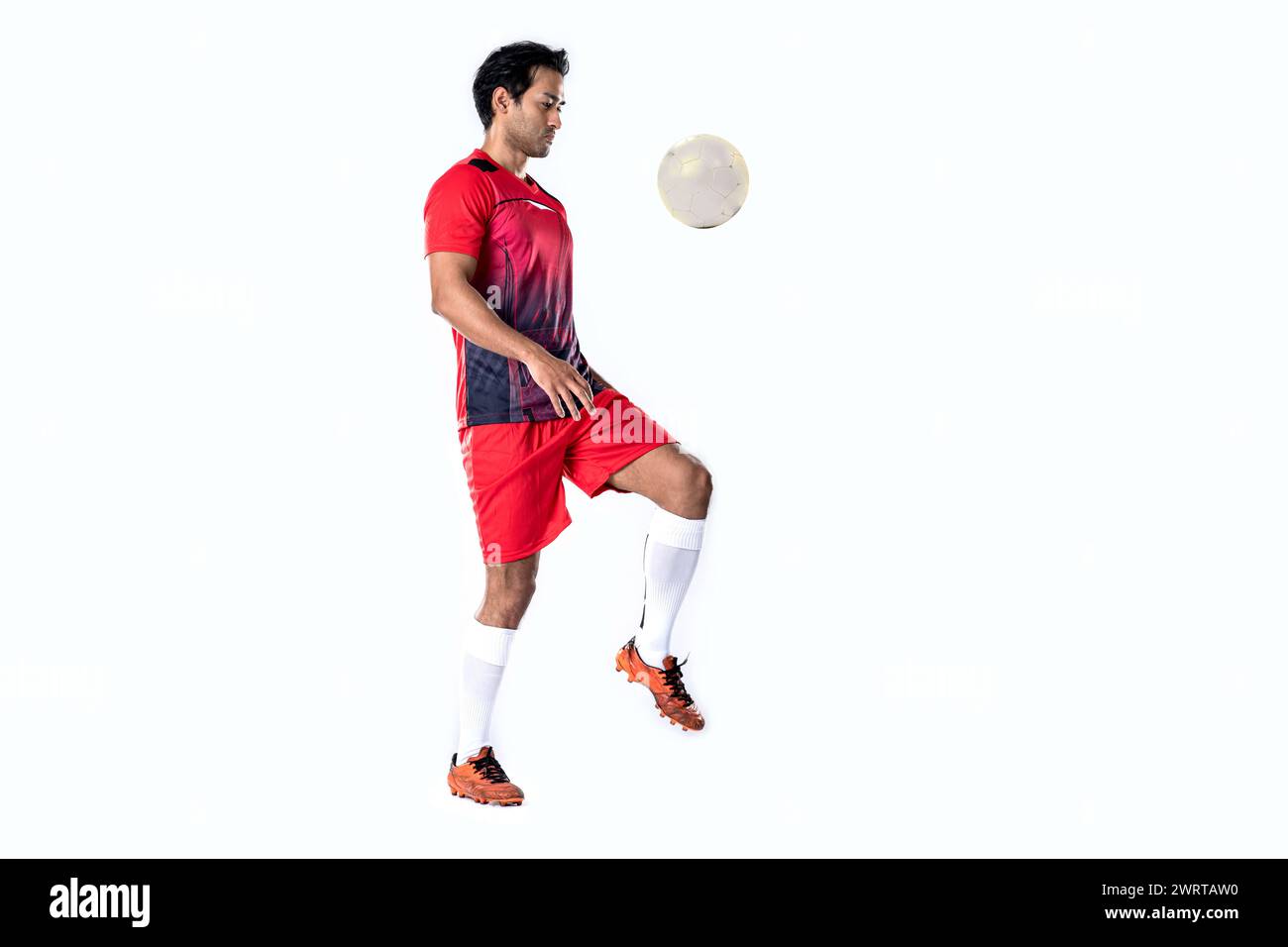 Giocatore di calcio professionista in uniforme da allenamento rossa posa su uno sfondo bianco concetto di calcio stile di vita attivo e sano Foto Stock Giocatore di calcio professionista in uniforme da allenamento rossa posa su uno sfondo bianco concetto di calcio stile di vita attivo e sano Foto Stock