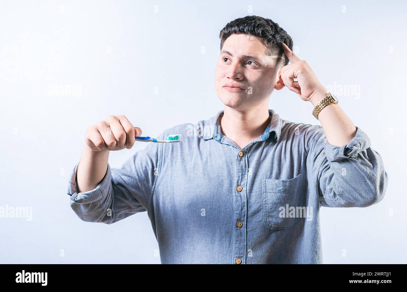 Uomo pensivo che tiene lo spazzolino isolato. Persona premurosa che tiene in mano lo spazzolino e guarda in alto in modo isolato Foto Stock